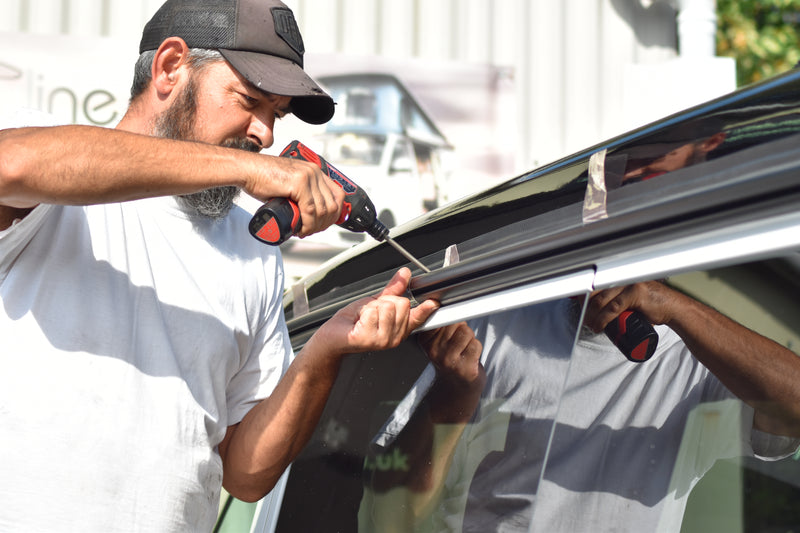 Person using a power tool to install an awning rail.