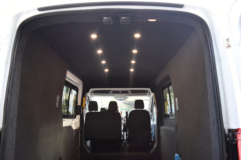Interior of a van with carpeting, black seats and visible ceiling lights.