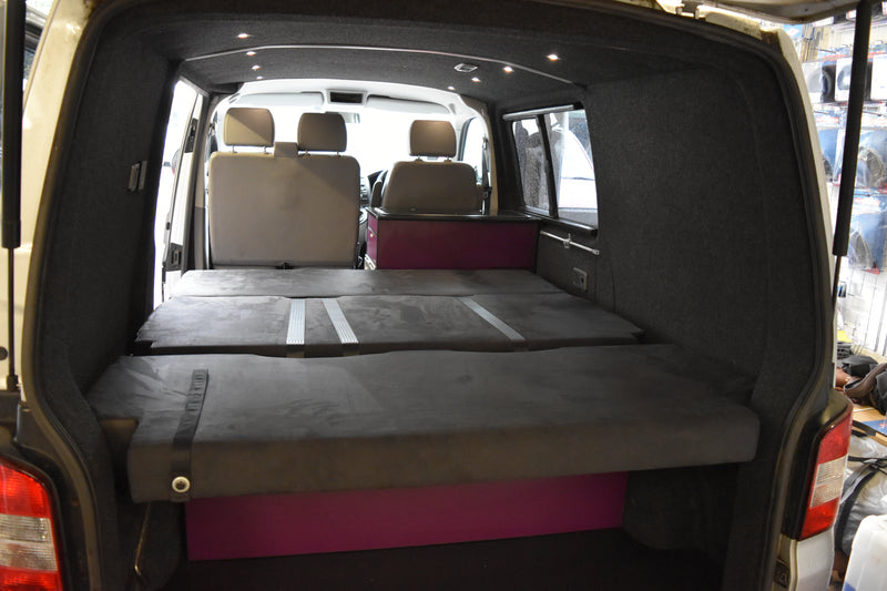 Van interior with a bed, showing the rear seats folded down.