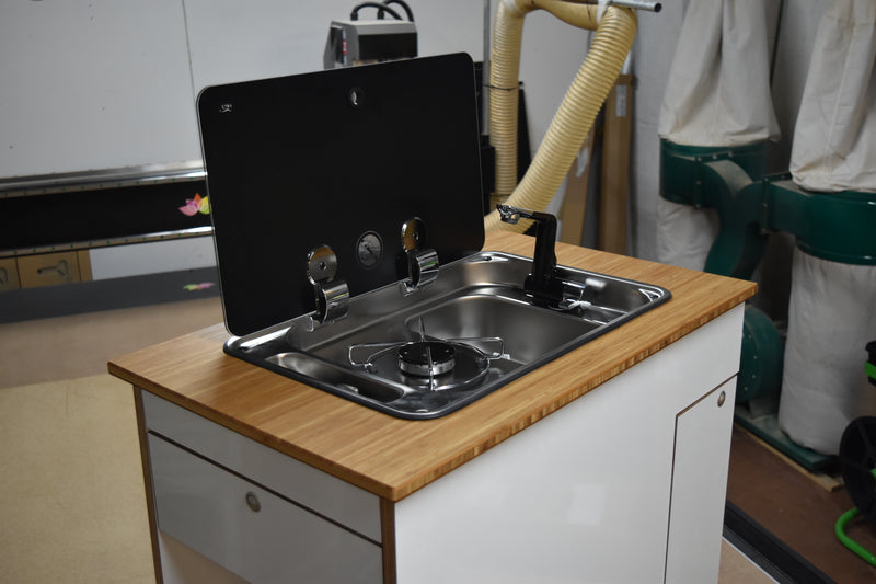 Compact kitchen setup with stove and sink on a wooden countertop.