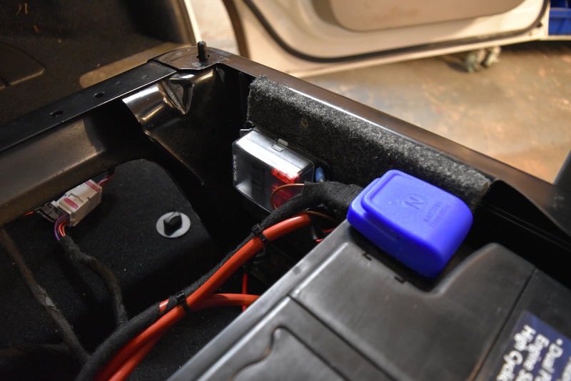 Close-up of a car battery with visible connections and inside a vehicle.