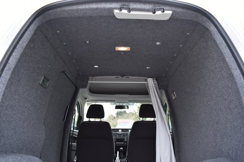 Interior of a Caddy van with gray carpeting and black seats.