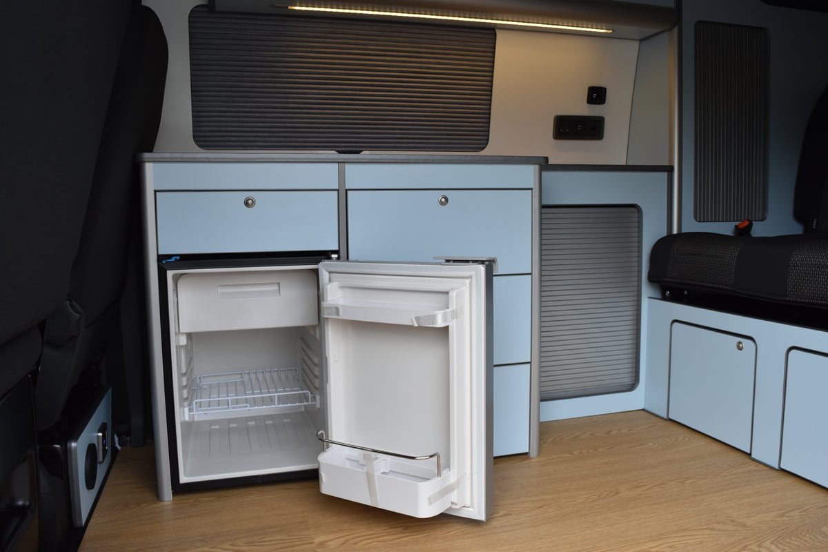 Camper Conversion with blue slimline cabinetry with built in fridge and a closed Vanshade blind