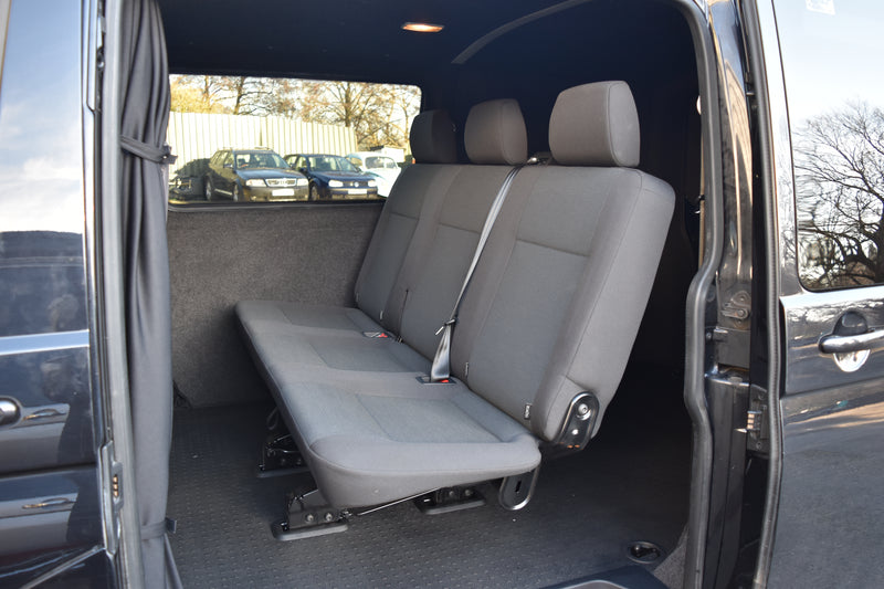 Grey interior of a van with seats and open door.