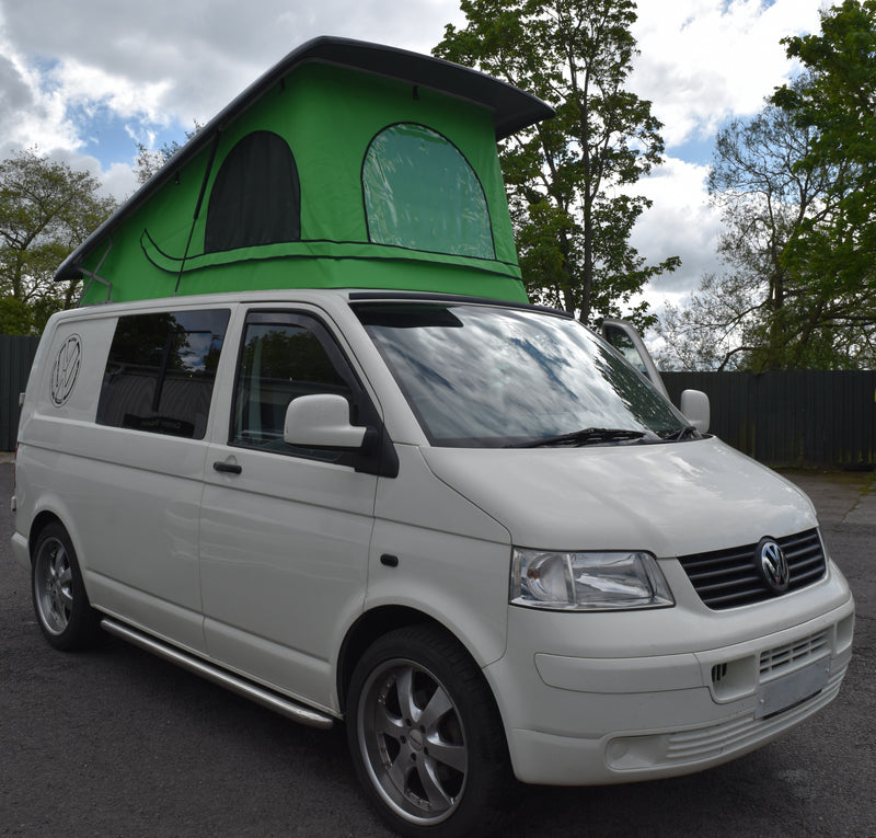 White van with a green roof canvas, parked outdoors on a cloudy day.