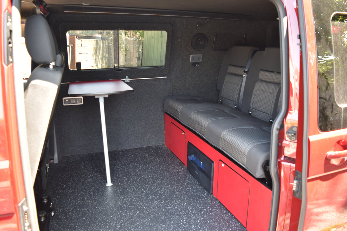 Red van interior with grey seats and a small table.