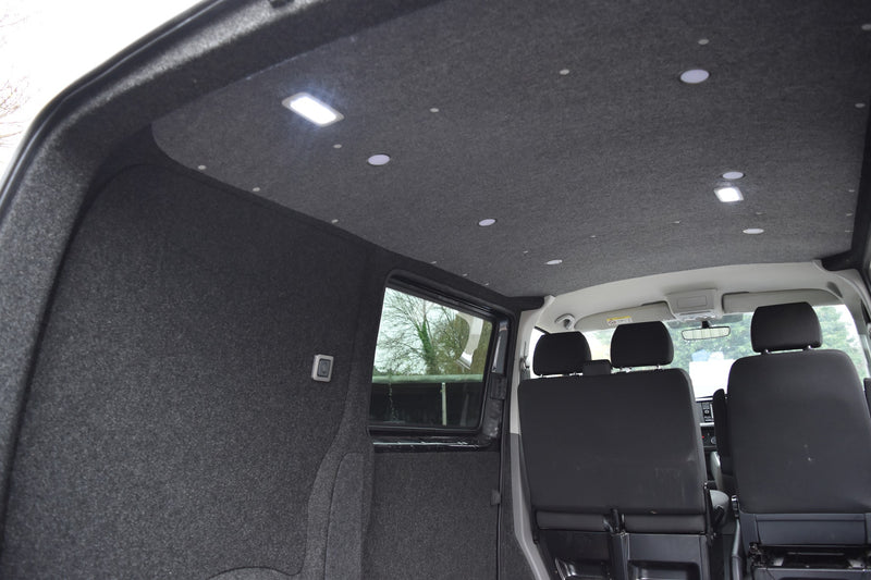 Interior of a vehicle with black carpeted floor and ceiling lights.