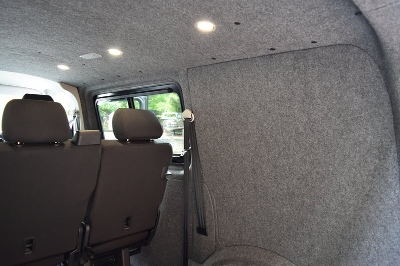 Back interior of a vehicle with grey carpeting and seats.