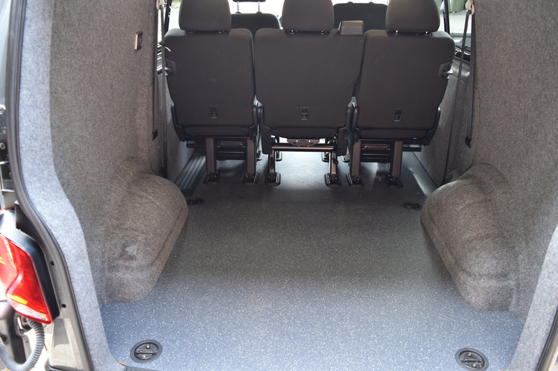 Van interior with hard wearing flooring, seats and carpet lined sides.