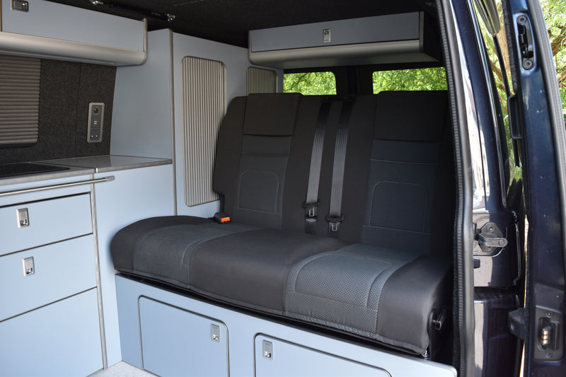 Camper van interior with baby blue cabinets and grey RIB bed