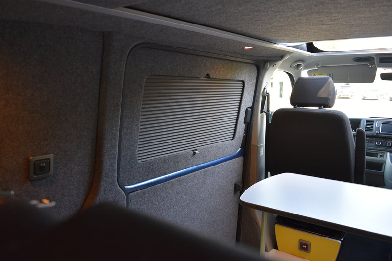 Interior of a van with a table and headrests and blinds on the window