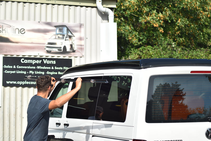Person fitting an awning rail to the side of a VW Transporter