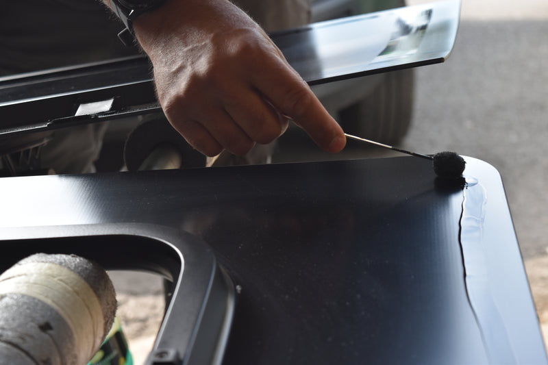 Person applying primer to a van window