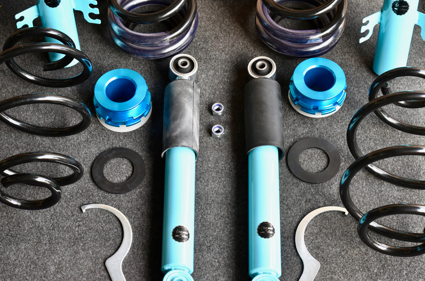 Automotive Vanslam shock absorbers with springs and other parts on a gray background