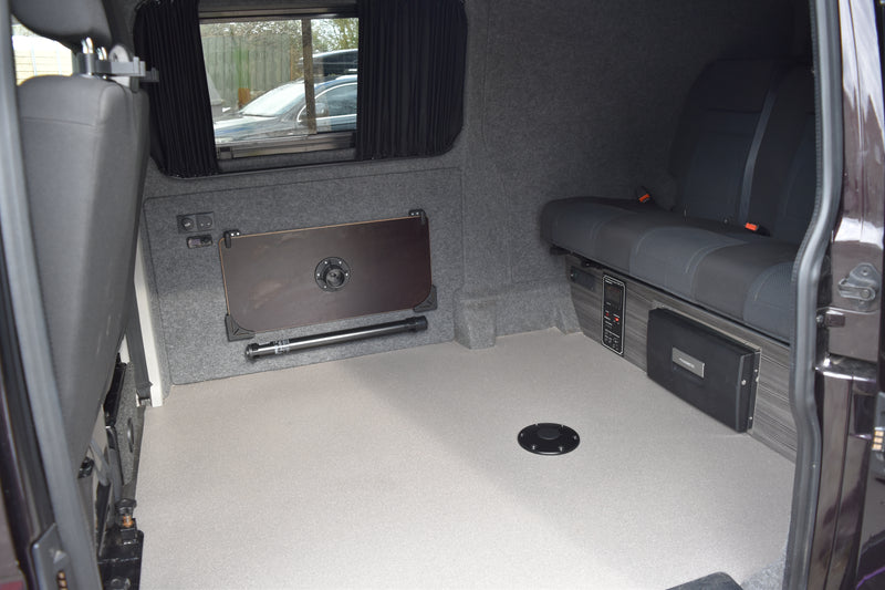 Van interior with grey seats and a flat floor, showing storage compartments.